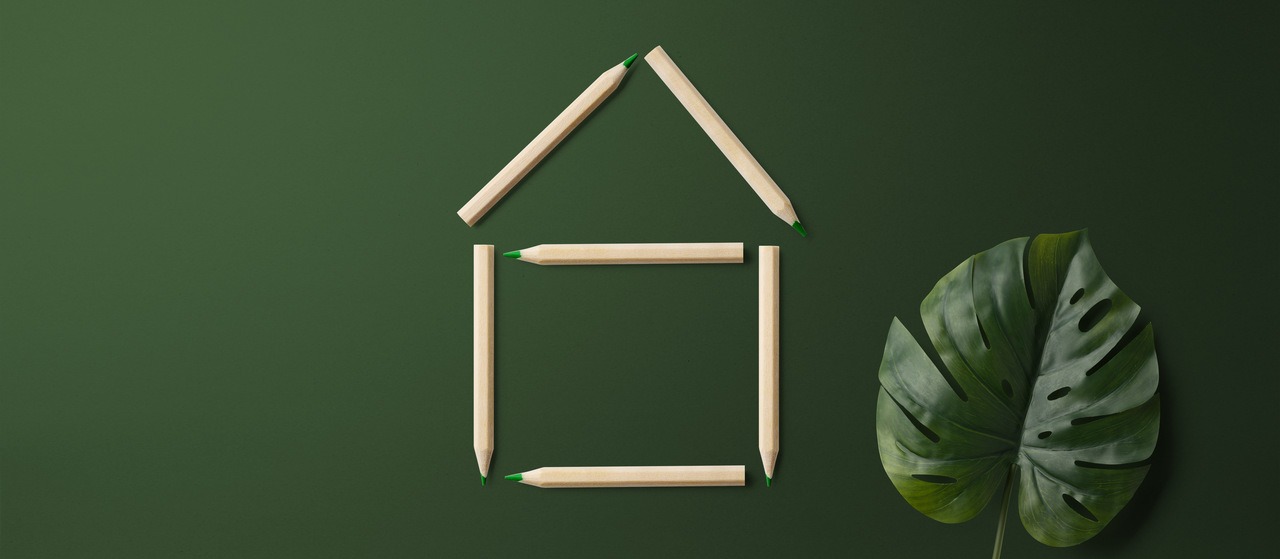 yeşil arkaplanda tahta çubuklarla yapılmış ev sembolü ve bir bitki yaprağı