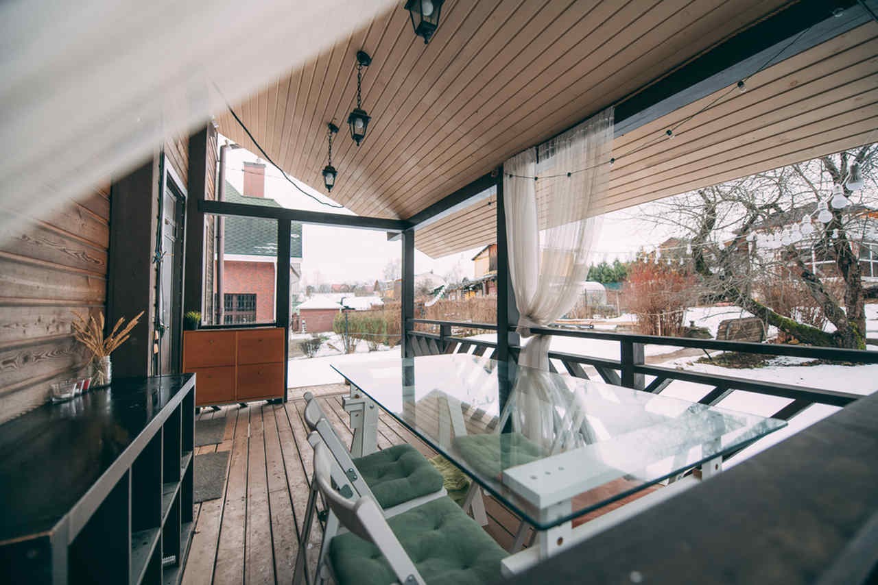 kar yağışlı bir havada içerisinde masa olan verandalı bir ev