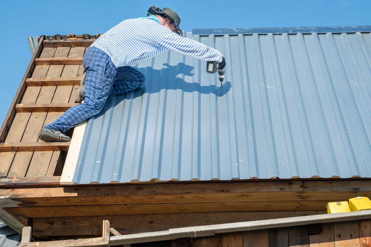 prefabrik ev çatısında galvaniz çelik uygulayan kişi